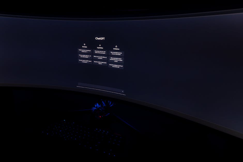 Close-up of a dark room with a curved monitor showing the ChatGPT interface on screen