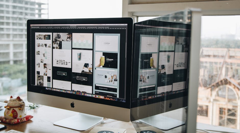 Dual monitors on a desk, showcasing web design in a modern office setting
