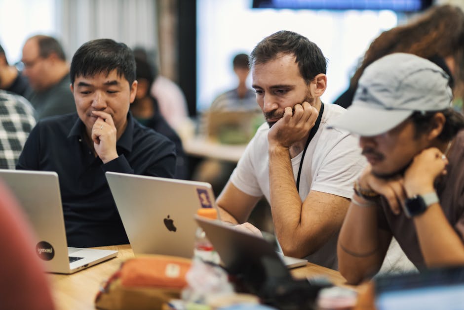 A diverse group of professionals working together on laptops in a modern office environment